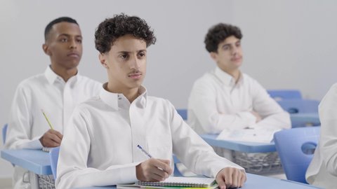 العودة إلى المدارس، الإستعداد للعام الدراسي الجديد، التعليم في السعودية، تأدية الواجبات المدرسية، مجموعة من الطلاب العربيين الخليجيين السعوديين يجلسون في مقاعدهم ويقومون بحل الواجب