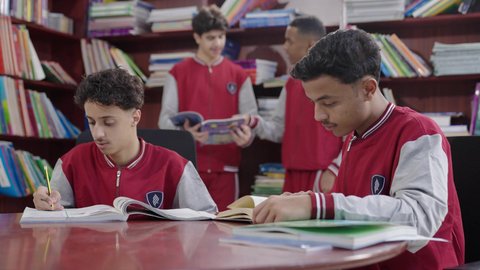 الاستمتاع بقراءة الكتب المدرسية، طلاب عربيين سعوديين خليجيين في المكتبة المدرسية، تأدية الواجبات المدرسية، التعليم في المملكة العربية السعودية