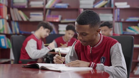 مفهوم التعليم الذاتي، مدارس المملكة المبتكره,تصوير مقرب لطالب عربي خليجي سعودي يجلس في المكتبة المدرسية, الاستمتاع بقراءة الكتب، بيئه مدرسيه تعليميه متطوره, مدارس أكاديميه في المملكة العربية السعودية، حل الواجبات المدرسية