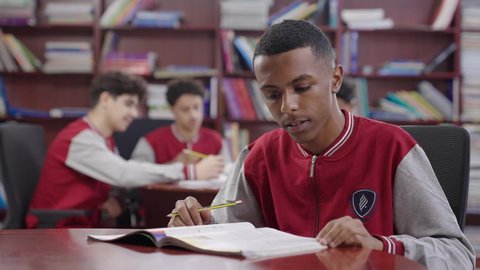 Innovative schools in the Kingdom, close-up of a Saudi Gulf Arab student sitting in the school library, the concept of self-directed learning, enjoying reading books, an advanced educational school environment, academic schools in the Kingdom of Saudi Arabia, doing homework.