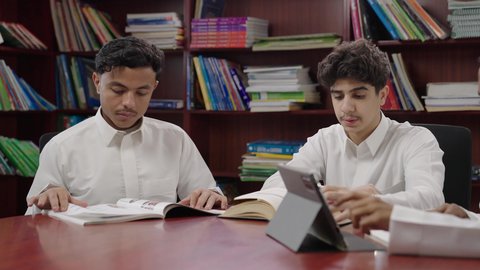 التعليم في المملكة العربية السعودية، الدراسة الجماعية والتعاون بين الزملاء، تأدية الواجبات المدرسية، استخدام التقنية الحديثة، الاستمتاع بقراءة الكتب المدرسية، مجموعة من طلاب عربيون خليجيون سعودوين يجلسون في المكتبة المدرسية