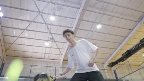 رياضات شبابية وأنشطة ترفيهية، القيام بتمرينات رياضة التنس، خوض المباريات والبطولات بتحدي وعزيمة، شاب عربي خليجي سعودي يرتدي ملابس رياضية يلعب مباراة كرة المضرب، التدرب على إتقان لعبة البادل، تعابير وإيماءات تدل على الحماس والاندماج بالتمرين