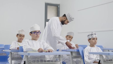 حوارات ودية بين الاستاذ والطلاب، المشاركة الفعالة للطلاب مع المدرسين، معلم عربي خليجي عماني يرتدي الدشداشة والكمة يقوم بمناقشة الدروس مع طلابه، جودة التعليم في سلطنة عمان ، التربية والتعليم بالمناهج المقررة للتلاميذ