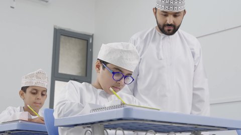 المشاركة الفعالة للطلاب مع المدرسين، معلم عربي خليجي عماني يرتدي الدشداشة والكمة يقوم بمناقشة الدروس مع طلابه، جودة التعليم في سلطنة عمان ، التربية والتعليم بالمناهج المقررة للتلاميذ، حوارات ودية بين الاستاذ والطلاب