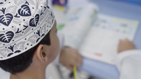 الإستعداد للعام الدراسي الجديد، تأدية الواجبات المدرسية، التعليم في سلطنة عمان، العودة إلى المدارس، مجموعة من الطلاب العربيين الخليجيين العمانيين يرتدون الدشداشة والكمة يجلسون في مقاعدهم ويقومون بحل الواجب