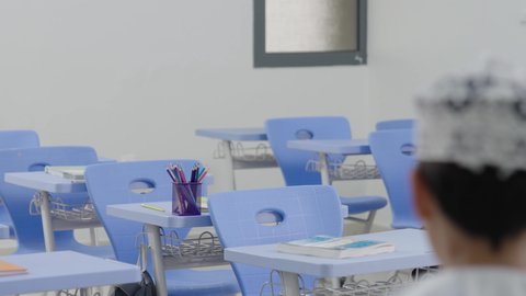 تأدية الواجبات المدرسية، الإستعداد للعام الدراسي الجديد، التعليم في سلطنة عمان، العودة إلى المدارس، مجموعة من الطلاب العربيين الخليجيين العمانيين يرتدون الدشداشة والكمة يجلسون في مقاعدهم ويقومون بحل الواجب