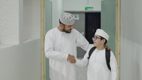 مدارس أكاديميه في سلطنة عمان ، وقت اللعب والترفيه, طالب عربي عماني خليجي يخرج الى بهو المدرسه مع معلمه،  ايماءات السعاده والمرح, الإستعداد للفصل الدراسي الجديد
