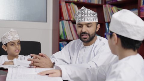 الاستمتاع بقراءة الكتب المدرسية ،المشاركة الفعالة للطلاب مع المدرسين،  معلم عربي خليجي عماني يرتدي الدشداشة والكمة يقوم بمناقشة الكتاب مع طلابه، جودة التعليم في سلطنة عمان ، مفهوم التعليم والثقافة ، حوارات ودية بين الاستاذ والطلاب