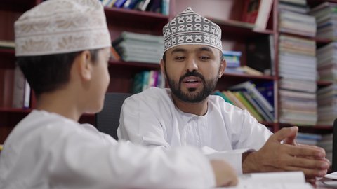 المشاركة الفعالة للطلاب مع المدرسين، الاستمتاع بقراءة الكتب المدرسية ، معلم عربي خليجي عماني يرتدي الدشداشة والكمة يقوم بمناقشة الكتاب مع طلابه، جودة التعليم في سلطنة عمان ، مفهوم التعليم والثقافة ، حوارات ودية بين الاستاذ والطلاب