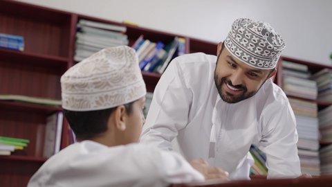 المشاركة الفعالة للطلاب مع المدرسين، الاستمتاع بقراءة الكتب المدرسية ، معلم عربي خليجي عماني يرتدي الدشداشة والكمة يقوم بمناقشة الكتاب مع طلابه، جودة التعليم في سلطنة عمان ، مفهوم التعليم والثقافة ، حوارات ودية بين الاستاذ والطلاب