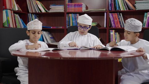 Browsing purposeful books, spending enjoyable time, the concept of education and curiosity, a group of Arab Omani Gulf students in the school library, enjoying reading school books, completing school assignments, education in the Sultanate of Oman.