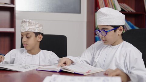 Spending enjoyable time, the concept of education and curiosity, a group of Arab Omani Gulf students in the school library, enjoying reading school books, doing school assignments, education in the Sultanate of Oman.