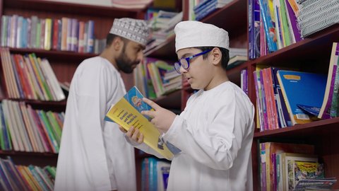 جودة التعليم في سلطنة عمان ، المشاركة الفعالة للطلاب مع المدرسين، الاستمتاع بقراءة الكتب المدرسية ، معلم عربي خليجي عماني يرتدي الدشداشة والكمة يقوم بمناقشة الكتاب مع طلابه، مفهوم التعليم والثقافة ، حوارات ودية بين الاستاذ والطلاب
