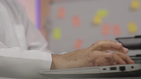 وظائف ومهن إدارية مكتبية، دمج التكنولوجيا الحديثة بالحياة العملية، النقر على لوحة المفاتيح، مفهوم ادخال البيانات، صناعة المحتويات النصية، تصوير مقرب ليد رجل عربي خليجي اماراتي يستخدم الحاسوب المحمول يقوم بالكتابة على لوحة المفاتيح