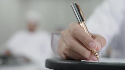 الاجتهاد في الدراسة لتحقيق النجاح والتميز الأكاديمي, تصوير مقرب ليد طالب عربي خليجي عماني يقوم بحل أسئلة الامتحان, اهداف التربية و التعليم, التعليم في سلطنه عمان