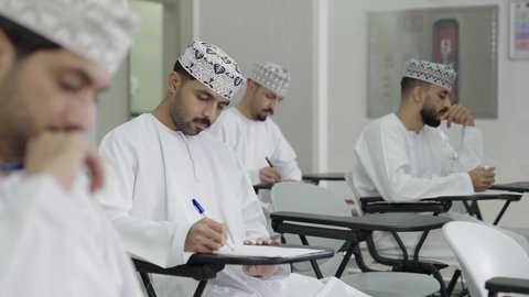 The pursuit of achieving success and academic excellence, a close-up shot of a group of Omani students solving exam questions, the goals of education and teaching, education in the Sultanate of Oman, expressions of contemplation and focus.