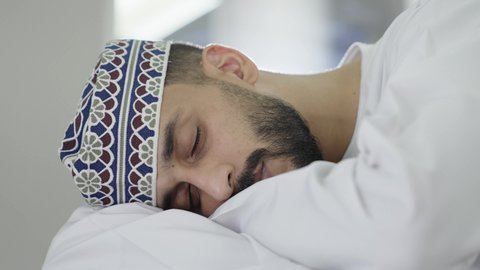 دور النوم الجيد في تحسين الحالة النفسية والجسمانية للطلاب ، التعب والاجهاد أثناء الدراسة، تصوير مقرب لطالب عربي خليجي عماني يرتدي الدشداشة و الكمه ياخذ قيلولة