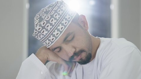 تعزيز الأداء الدراسي من خلال الراحة والنوم ، التعب والاجهاد أثناء الدراسة، تصوير مقرب لطالب عربي خليجي عماني يرتدي الدشداشة و الكمه ياخذ قيلولة