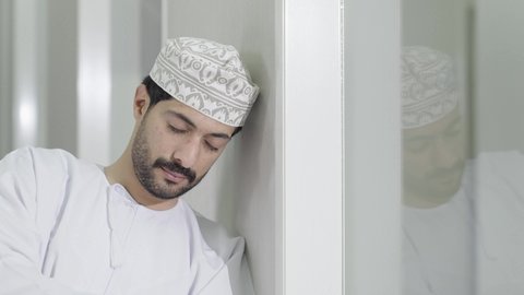 التعب والاجهاد أثناء الدراسة, أهمية الراحة والنوم الجيد في تعزيز الصحة العقلية والجسدية للطلاب،تصوير مقرب لطالب عربي خليجي عماني يرتدي الدشداشة و الكمه ياخذ قيلولة