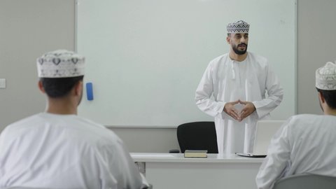 الإنتباه والتركيز والإستماع إلى المحاضرة، تطوير أساليب التعليم الجامعي في سلطنه عمان،معلم عربي خليجي عماني يرتدي الدشداشة و الكمة يقوم بشرح المحاضرة للطلاب، ورش عمل ودورات تدريبية، التعليم الجامعي العماني