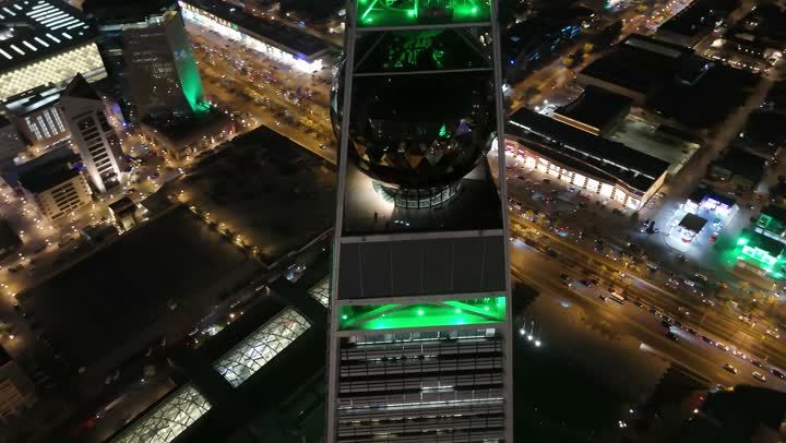 Celebrating Saudi National Day on September 23, skyscrapers, tourist facilities, and hotels are lit up in green. Saudi Arabia's economic and urban renaissance. Aerial drone footage of the Al Faisaliah Tower in Riyadh. The sophisticated architectural style of the Al Olaya Towers. King Fahd Road in the Kingdom.