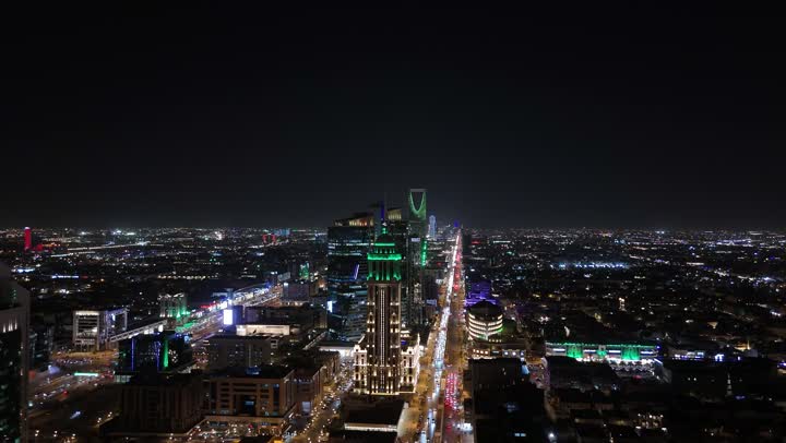 Commercial and residential facilities and modern buildings, aerial drone footage of traffic in the capital's illuminated streets at night, attention to infrastructure in Riyadh, the architectural art of towers and skyscrapers in Saudi Arabia, urban growth and progress