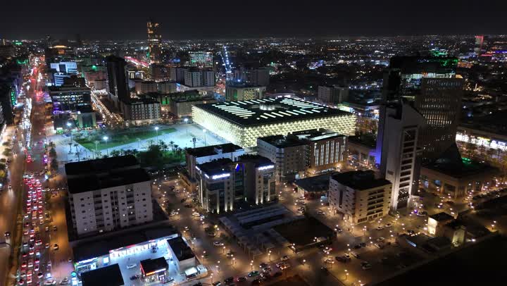 الاهتمام بالبنية التحتية في مدينة الرياض، الفن الهندسي المعماري للابراج وناطحات السحاب في المملكة العربية السعودية، الشوارع المعبدة والطرقات، المنشأت التجارية والسكنية والمباني على الطراز الحديث، تصوير درون جوي لحركة مرور السيارات في شوارع العاصمة المضيئة ليلا