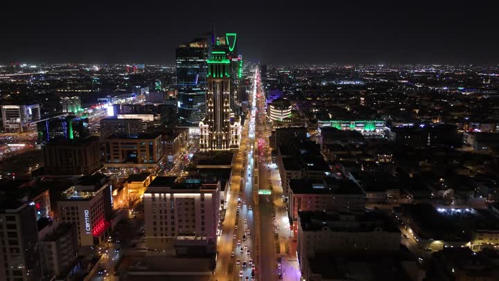 Commercial and residential facilities and modern buildings, aerial drone footage of traffic in the capital's illuminated streets at night, attention to infrastructure in Riyadh, the architectural art of towers and skyscrapers in Saudi Arabia, urban growth and progress