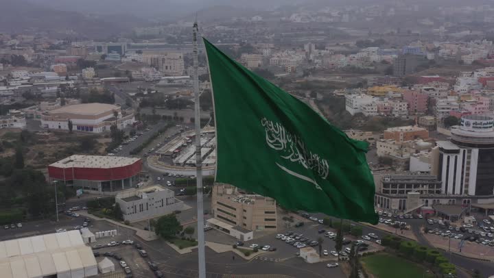 سارية العلم السعودي الأخضر المرفرف في الهواء في دوار الملك فيصل، الفخر والاعتزاز بالانتماء الى الوطن, المعالم المشهورة في مدينة أبها بمنطقة عسير جنوب غرب المملكة