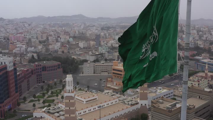 سارية العلم السعودي الأخضر المرفرف في الهواء في دوار الملك فيصل، الفخر والاعتزاز بالانتماء الى الوطن, المعالم المشهورة في مدينة أبها بمنطقة عسير جنوب غرب المملكة