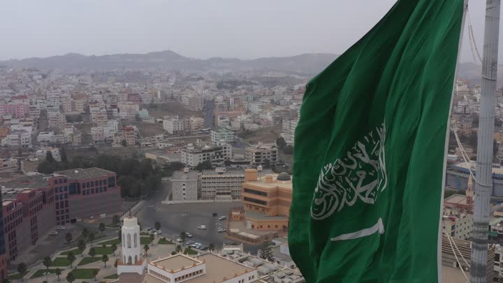 سارية العلم السعودي الأخضر المرفرف في الهواء في دوار الملك فيصل، الفخر والاعتزاز بالانتماء الى الوطن, المعالم المشهورة في مدينة أبها بمنطقة عسير جنوب غرب المملكة