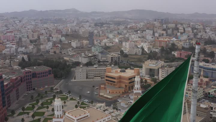 سارية العلم السعودي الأخضر المرفرف في الهواء في دوار الملك فيصل، الفخر والاعتزاز بالانتماء الى الوطن, المعالم المشهورة في مدينة أبها بمنطقة عسير جنوب غرب المملكة