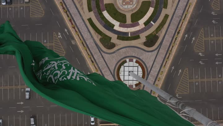 سارية العلم السعودي الأخضر المرفرف في الهواء في دوار الملك فيصل، الفخر والاعتزاز بالانتماء الى الوطن, المعالم المشهورة في مدينة أبها بمنطقة عسير جنوب غرب المملكة