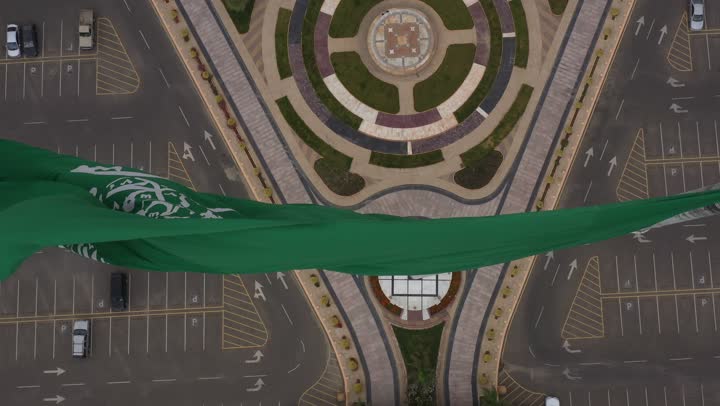 سارية العلم السعودي الأخضر المرفرف في الهواء في دوار الملك فيصل، الفخر والاعتزاز بالانتماء الى الوطن, المعالم المشهورة في مدينة أبها بمنطقة عسير جنوب غرب المملكة