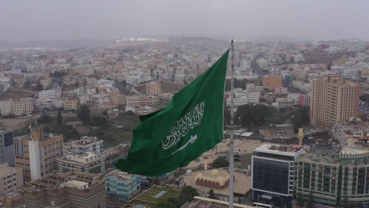 سارية العلم السعودي الأخضر المرفرف في الهواء في دوار الملك فيصل، الفخر والاعتزاز بالانتماء الى الوطن, المعالم المشهورة في مدينة أبها بمنطقة عسير جنوب غرب المملكة