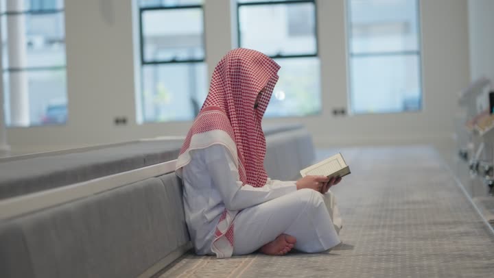 تلاوة وحفظ القرأن الكريم, العبادة و التقرب الى الله, الخلوة داخل بيت الله, رجل عربي خليجي سعودي مسلم يرتدي الشماغ والثوب التقليدي يجلس داخل المسجد و يقرأ من المصحف الشريف