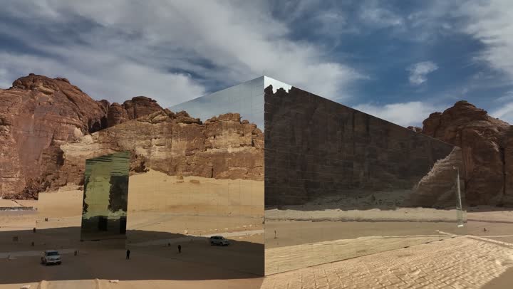 معلم سياحي تاريخي ترفيهي، قاعة المرايا للحفلات الموسيقية وسط صحراء العلا في المملكة العربية السعودية، انعكاس الطبيعة الصخرية والتكوين والتشكيل الصخري على الزجاج في النهار، رحلات السفاري الترفيهية الممتعة