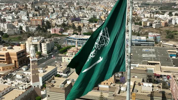 سارية العلم السعودي الأخضر المرفرف في الهواء في دوار الملك فيصل، الفخر والاعتزاز بالانتماء الى الوطن, المعالم المشهورة في مدينة أبها بمنطقة عسير جنوب غرب المملكة