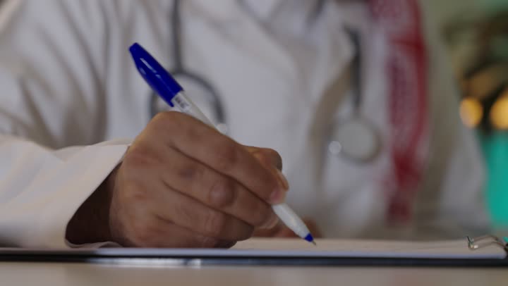مفهوم الطب والرعاية الصحية، إدارة شؤون الأعمال عبر جهاز تقني حديث ومتطور، العمل فى القطاع الصحي، العمل على الحاسوب المحمول  ،طبيب عربي خليجي سعودي يرتدي المعطف الابيض والسماعه  يقوم باستخدام الحاسوب المحمول وتدوين الملاحظاات ، العيادة الطبية في السعودية