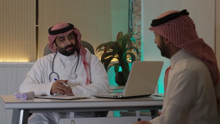 تقديم الاستشارات الطبية والخدمات الصحية، طبيب عربي خليجي سعودي يرتدي المعطف الطبي و السماعة الطبية ،يقوم بتقديم الرعاية الطبية للمريض  , مفهوم الطب والرعاية الصحية
