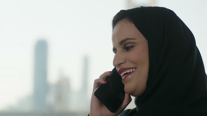 التواصل مع الأهل والأصدقاء عبر الجوال، الدردشة عبر الانترنت, سيدة عربية خليجية سعودية ترتدي العباءة والحجاب تحمل بيدها هاتف محمول , استخدام الأجهزة الحديثة والمتطورة، تصفح وسائل التواصل الاجتماعي.