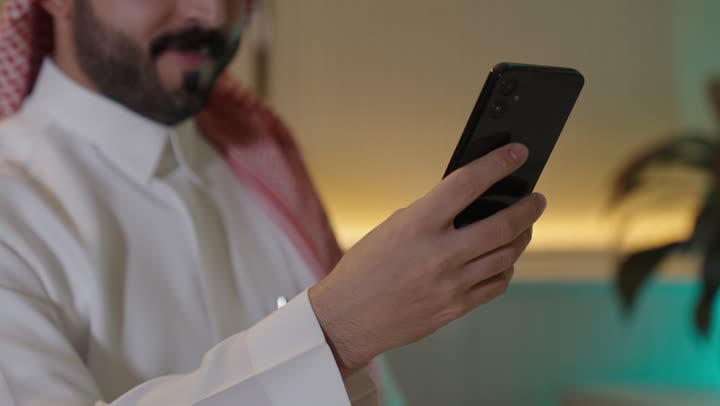 الدردشة عبر الانترنت, التواصل مع الأهل والأصدقاء عبر الجوال، رجل عربي خليجي سعودي يرتدي الزي التقليدي والشماغ يحمل بيده هاتف محمول , استخدام الأجهزة الحديثة والمتطورة، تصفح وسائل التواصل الاجتماعي.