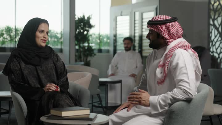 The comfortable work environment in Saudi companies, dialogue and discussion among colleagues, a group of Arab Gulf Saudi employees sitting inside the company headquarters, exchanging experiences and information to achieve goals.