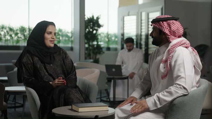 بيئة العمل المريحة في الشركات السعودية، الحوار و النقاش بين الزملاء،  مجموعة من موظفين عربيين خليجيين سعوديين يجلسون  داخل مقر الشركة، تبادل الخبرات والمعلومات لتحقيق الاهداف