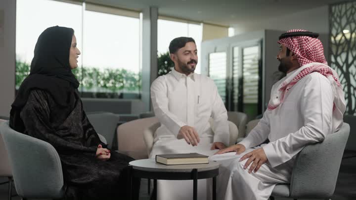 The comfortable work environment in Saudi companies, dialogue and discussion among colleagues, a group of Arab Gulf Saudi employees sitting inside the company headquarters, exchanging experiences and information to achieve goals.