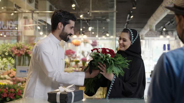 ايماءات تدل على الفرح والسعاده، متاجر ومحلات بيع الورود والزهور الطبيعية للأعياد والمناسبات, زوجان عربيان خليجيان سعوديان يقومان بشراء باقة ورد احمر طبيعي من البائع