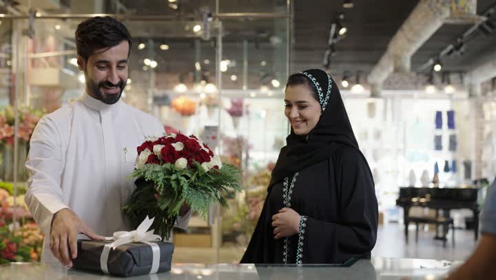 ايماءات تدل على الفرح والسعاده، متاجر ومحلات بيع الورود والزهور الطبيعية للأعياد والمناسبات, زوجان عربيان خليجيان سعوديان يقومان بشراء باقة ورد احمر طبيعي من البائع