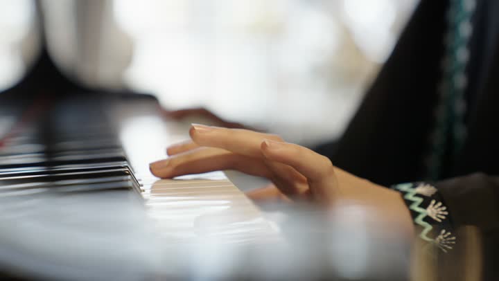 امراه عربية سعودية خليجية ترتدى العباءه والحجاب تقوم بالعزف على آلة البيانو , آلات موسيقية , مواهب فنية وفنون موسيقية .