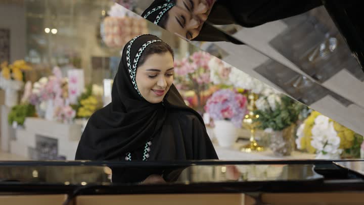امراه عربية سعودية خليجية ترتدى العباءه والحجاب تقوم بالعزف على آلة البيانو , آلات موسيقية , مواهب فنية وفنون موسيقية .