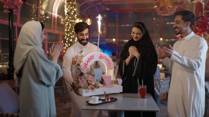 إيماءات السعادة والمفاجأة والفرح، زينة الأعياد والمناسبات السعيدة، رجل عربى خليجي سعودي يقوم بالاحتفال بعيد ميلاد زوجته في إحدى المطاعم السعودية، قضاء وقت ممتع مع الأهل والأصدقاء، كعكة عيد ميلاد